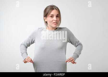 Perdere il concetto a peso. Caucasica donna sottile che mostra che il suo vestito è grande per lei. Risultato della dieta. Foto Stock