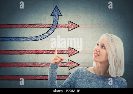 Donna sorridente che mostra frecce di fantasia con il dito indice per un cambiamento di direzione e di piegatura andando verso l'alto. Diverse aziende di pensare, di creatività e di comp Foto Stock