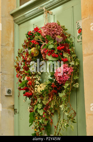 Multi-corona di fiori colorati con hydrangeaon ed edera su una porta di legno Foto Stock