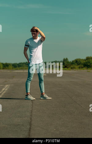 Giovani maschi adulti in piedi fuori nel sole Foto Stock