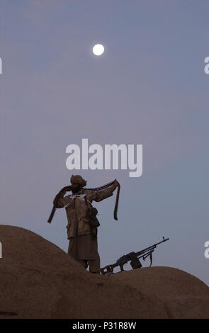 Afghanistan, (GEN. 1, 2002) -- Un Anti-Taliban forze (ATF) fighter avvolge un dei nastri di munizioni intorno al suo corpo come ATF aiuto di personale Foto Stock