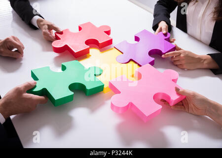 Gruppo di imprenditori risolvere colorato Puzzle sulla scrivania Foto Stock