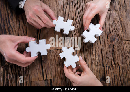 Gruppo di imprenditori risolvendo puzzle sulla scrivania Foto Stock