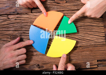 Gli imprenditori pezzi di collegamento di multi colore grafico a torta sulla scrivania in legno Foto Stock