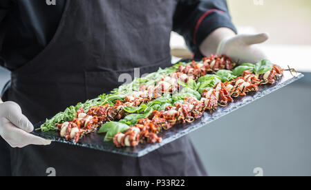 Chef in hotel o al ristorante tiene nelle sue mani scheda di ardesia con insalata caprese. Foto Stock