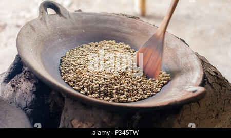 Master girarrosti arrosto manualmente i chicchi di caffè in un legno-sparò stufa vicino Banyuwangi, Java, Indonesia Foto Stock