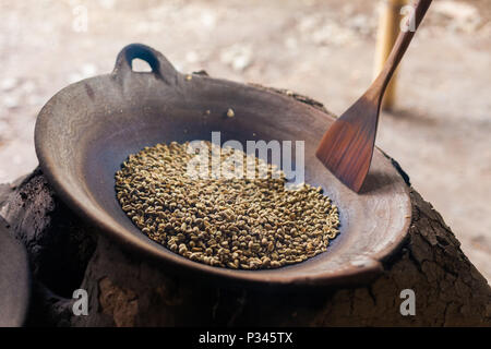 Master girarrosti arrosto manualmente i chicchi di caffè in un legno-sparò stufa vicino Banyuwangi, Java, Indonesia Foto Stock