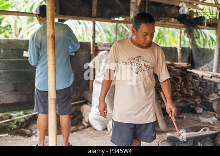 Master girarrosti arrosto manualmente i chicchi di caffè in un legno-sparò stufa vicino Banyuwangi, Java, Indonesia Foto Stock