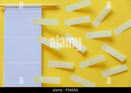 Moltitudine di vuoto adesivi giallo fisso su un notebook a spirale e la scrivania in ufficio Foto Stock