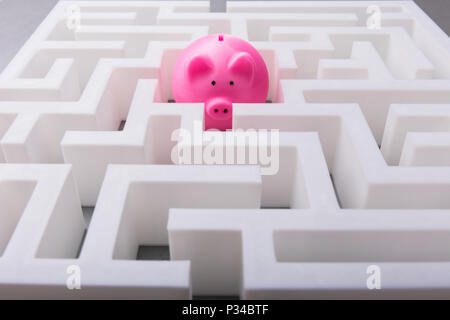 Close-up di Rosa Piggybank nel centro di bianco labirinto Foto Stock