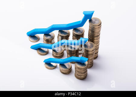 Impilate le monete d'oro con crescente le frecce blu su sfondo riflettente Foto Stock