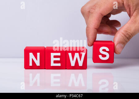 Close-up di mano di una persona facendo parola News con il rosso i blocchi cubici Foto Stock