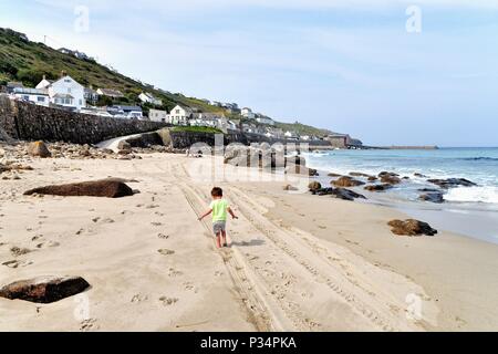 Little Boy lungo la spiaggia sabbiosa a Sennen Cove Cornwall Inghilterra REGNO UNITO Foto Stock