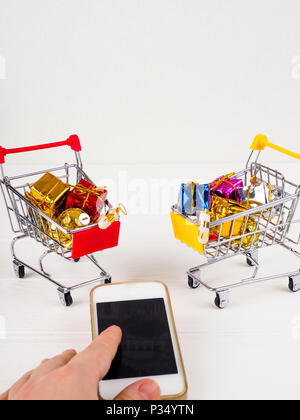 Carrello per supermercati e il telefono cellulare, il concetto di shopping online in Internet. Foto Stock