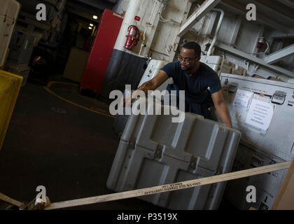 180615-N-AH771-0032 U.S. 5TH FLOTTA AREA DI OPERAZIONI (15 giugno 2018) specialista della logistica marinaio Anthony Wallace, da Los Angeles, organizza i contenitori di spedizione nell'hangar bay di wasp-classe assalto anfibio nave USS Iwo Jima (LHD 7), 15 giugno 2018. Iwo Jima, homeported a Mayport Fla., è sulla distribuzione per gli Stati Uniti Quinta Flotta area di operazioni a sostegno della sicurezza marittima operazioni per rassicurare gli alleati e partner e preservare la libertà di navigazione e il libero flusso di commercio nella regione. (U.S. Foto di Marina di Massa lo specialista di comunicazione di terza classe Daniel C. Coxwest/rele Foto Stock