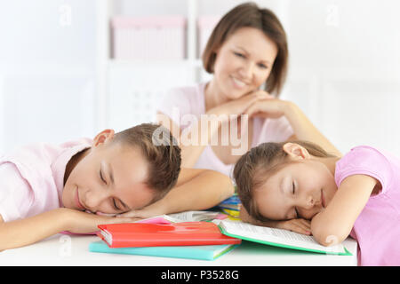 Madre guardando i bambini stanchi dopo aver fatto i compiti di scuola Foto Stock