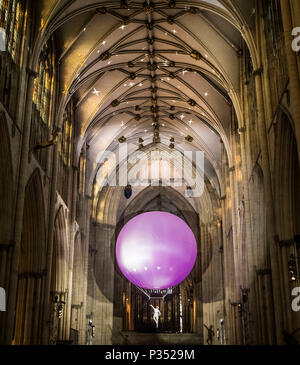 Un acrobat esegue sospendere al di sotto di una gigante palla gonfiabile galleggiante attraverso York Minster la navata, durante una performance di Heliosphere dal sogno del motore. Foto Stock