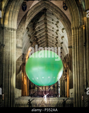 Un acrobat esegue sospendere al di sotto di una gigante palla gonfiabile galleggiante attraverso York Minster la navata, durante una performance di Heliosphere dal sogno del motore. Foto Stock