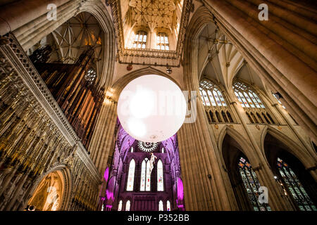 Un acrobat esegue sospendere al di sotto di una gigante palla gonfiabile galleggiante attraverso York Minster la navata, durante una performance di Heliosphere dal sogno del motore. Foto Stock