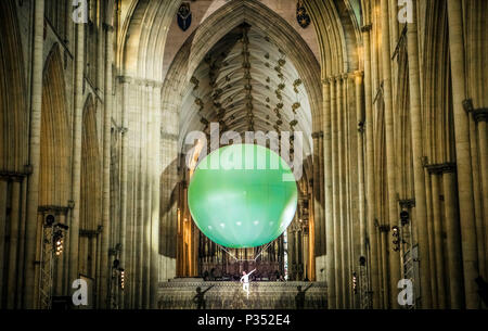 Un acrobat esegue sospendere al di sotto di una gigante palla gonfiabile galleggiante attraverso York Minster la navata, durante una performance di Heliosphere dal sogno del motore. Foto Stock