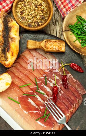 Tagliate a fettine sottili il tedesco il prosciutto della Foresta Nera con fette di pane ciabatta. Tagliate a fette e prosciutto affumicato con schwarzwald prosciutto o prosciutto. Cibo tradizionale tedesco Foto Stock