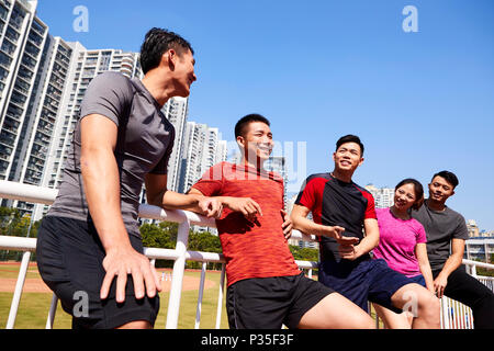 Un gruppo di giovani asiatici adulti parlare in chat rilassante in uno stadio durante il riposo durante l'esercizio Foto Stock