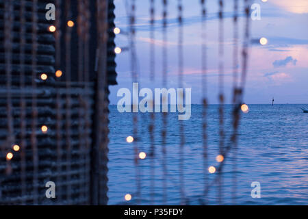 Stringhe di conchiglie e le luci di natale su un isola tropicale al tramonto Foto Stock