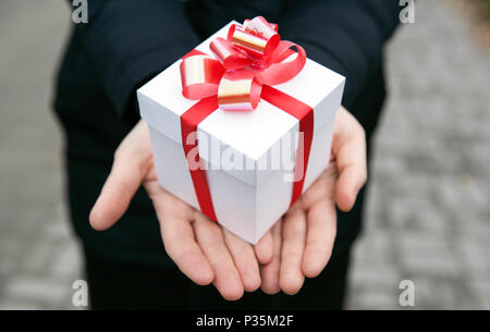 Mani femminili vi danno una confezione regalo close up Foto Stock