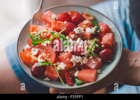 Giovane Azienda freschi e saporiti Insalata estiva con frutti, bacche e ortaggi. Vista da sopra, primo piano Foto Stock