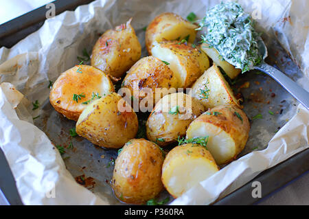Patate fritte su vassoi da forno con crosta dorata e salsa di aneto Foto Stock