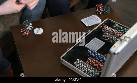 Voce maschile le mani prendere le carte e fiche da poker caso sul tavolo Foto Stock