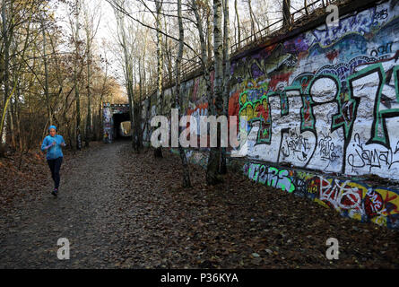 Berlino, Germania, donna jogging lungo un graffiti-parete cosparsa Foto Stock