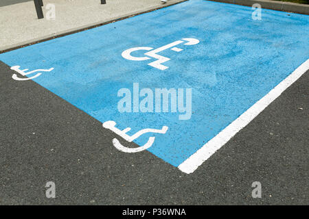 Portatori di handicap internazionale simbolo dipinto in blu luminoso su un centro commerciale spazio parcheggio. Lo spazio è chiaramente indicata su entrambi i lati con ulteriori Foto Stock