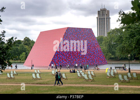 La gente camminare passato Christo la prima volta nel Regno Unito il lavoro all'aperto, Mastaba, a 20m alto installazione composta di 7,506 impilate orizzontalmente di barili e che sarà 20m, 30m di larghezza e 40m di lunghezza, per essere visualizzato sul lago a serpentina fino al 23 settembre 2018. Foto Stock