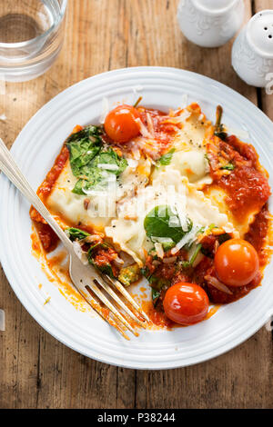 Gli spinaci e ricotta ravioli in salsa di pomodoro con pomodori ciliegia, formaggio pecorino e pinoli Foto Stock