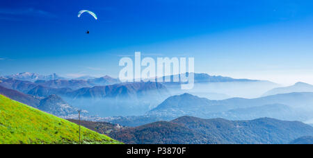 Parapendio sopra la città di Lugano, San Salvatore montagna e lago di Lugano vista dal Monte Lema, Canton Ticino, Svizzera Foto Stock