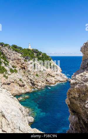 Mallorca, blu chiaro l'acqua di mare nella baia tra rocce e faro di Capdepera. Foto Stock