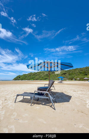 Lettini e ombrellone su una spiaggia di sabbia bianca allo Shangri La Rasa Ria Hotel e Resort in Kota Kinabalu, Borneo sul bordo del Mare della Cina del Sud Foto Stock