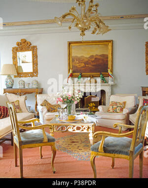 Grande dipinto sopra il camino in Toscana sala da disegno con cornici dorate e sedie comode poltrone color crema Foto Stock