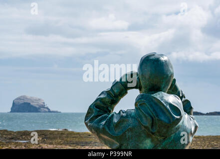 Milsey Bay, North Berwick, East Lothian, Scozia, Regno Unito, 18 giugno 2018. Una vita di bronzo dimensioni statua chiamata Il Watcher dallo scultore Kenny Hunter si affaccia al Bass Rock gannet colonia, la più grande del Nord colonia gannet Foto Stock