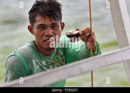 Alloggiamenti per North Bay, Philippines-October 15, 2016: pescatore filippino nella sua barca di legno si avvicina un turista bangka offrendo la sua cattura di ostriche alla v Foto Stock