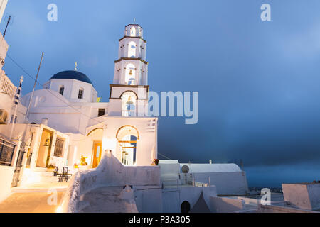 Il Pyrgos, Grecia - Maggio 2018: vista della chiesa ortodossa e della torre campanaria in Pyrgos centro città - Santorini Island, Grecia. Orientamento verticale, vista al tramonto. Foto Stock