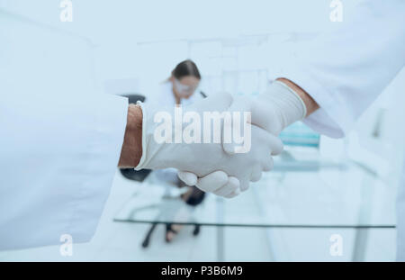 I medici in camice da laboratorio si salutano con handshake Foto Stock
