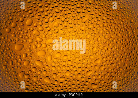 In prossimità di una di gocce di acqua su un gradiente di colore arancione sfondo, coperto con gocce di acqua : la condensazione. Foto Stock