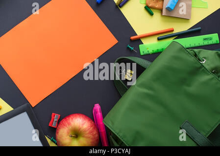 Concetto di ritorno a scuola zaino Apple articoli di cancelleria su sfondo nero. Vista superiore laici piatta Foto Stock