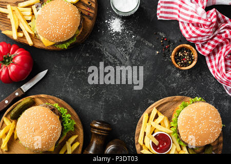 Gli hamburger e patatine fritte in pietra scura sullo sfondo, vista dall'alto con copia spazio. In casa hamburger e patatine fritte. Fast food o concetto BBQ Foto Stock