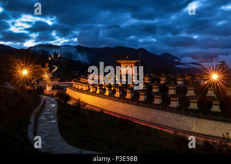 108 memorial chortens di Dochula splendente nella sua gloria al tramonto con le nuvole pesanti dando in azienda al cielo blu Foto Stock