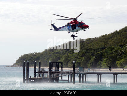 Vittima di incidenti in barella essendo winched a bordo in bilico Salvataggio in elicottero, Isola Fitzroy, della Grande Barriera Corallina, Queensland, Australia. No signor o PR Foto Stock