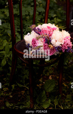 La sposa il bouquet di peonie è su una vecchia sedia in legno. Fiorai matrimonio Foto Stock