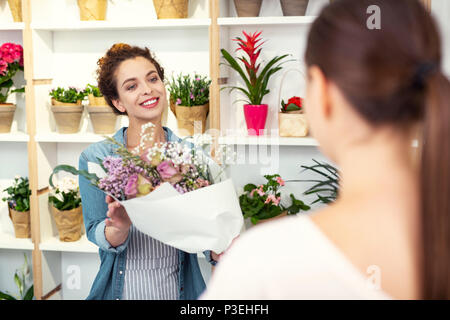 Felice bella donna offrendo bouquet Foto Stock